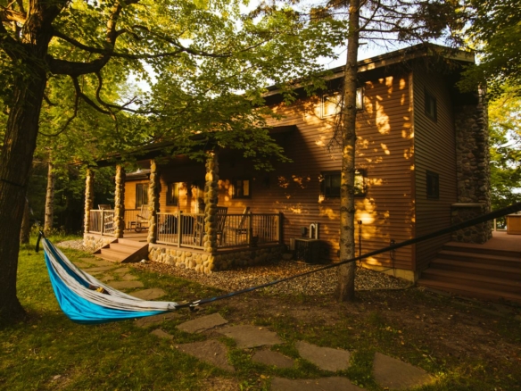 Cozy log cabin nestled among trees in Pelican Rapids, Minnesota at sunset.